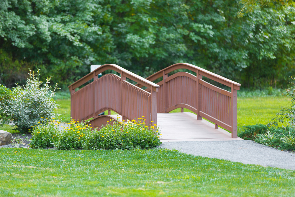 Bridge over a creek at Hatfield Village Apartments surrounded by trees and greenery