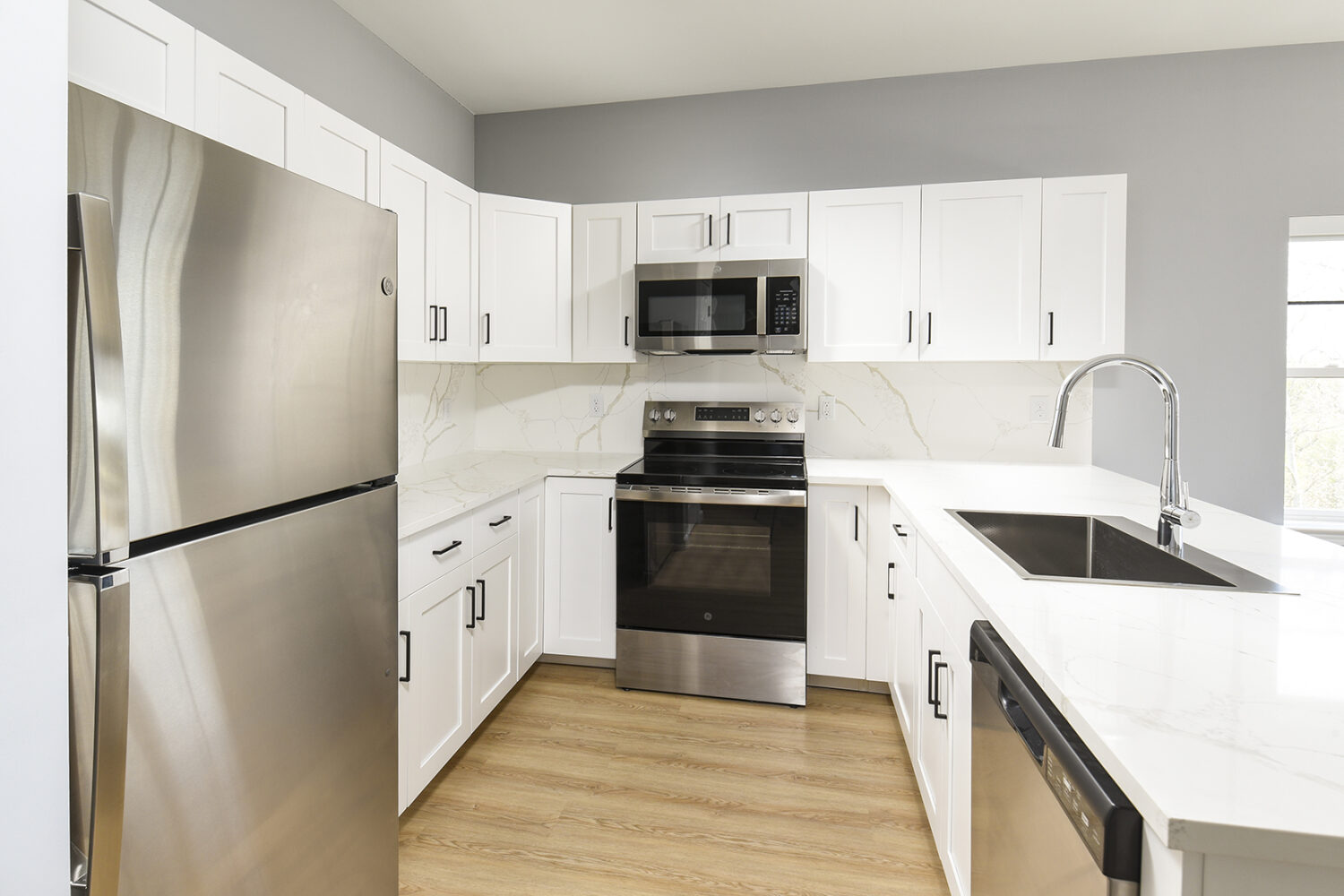 Kitchen With Efficient, Modern Stainless Steel Appliances and Quartz Countertops and Pendant Lighting