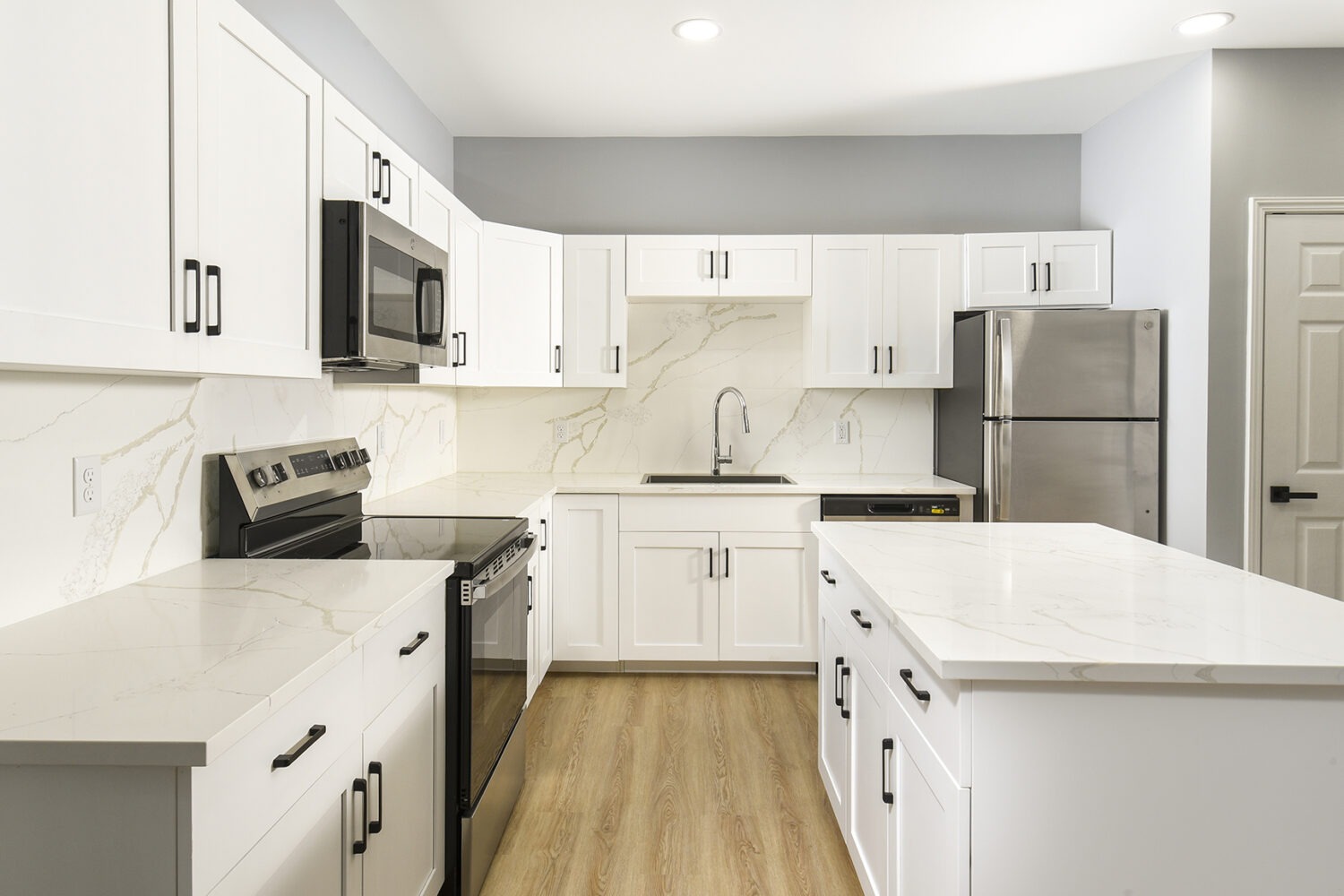 Kitchen With Efficient, Modern Stainless Steel Appliances and Quartz Countertops and Pendant Lighting