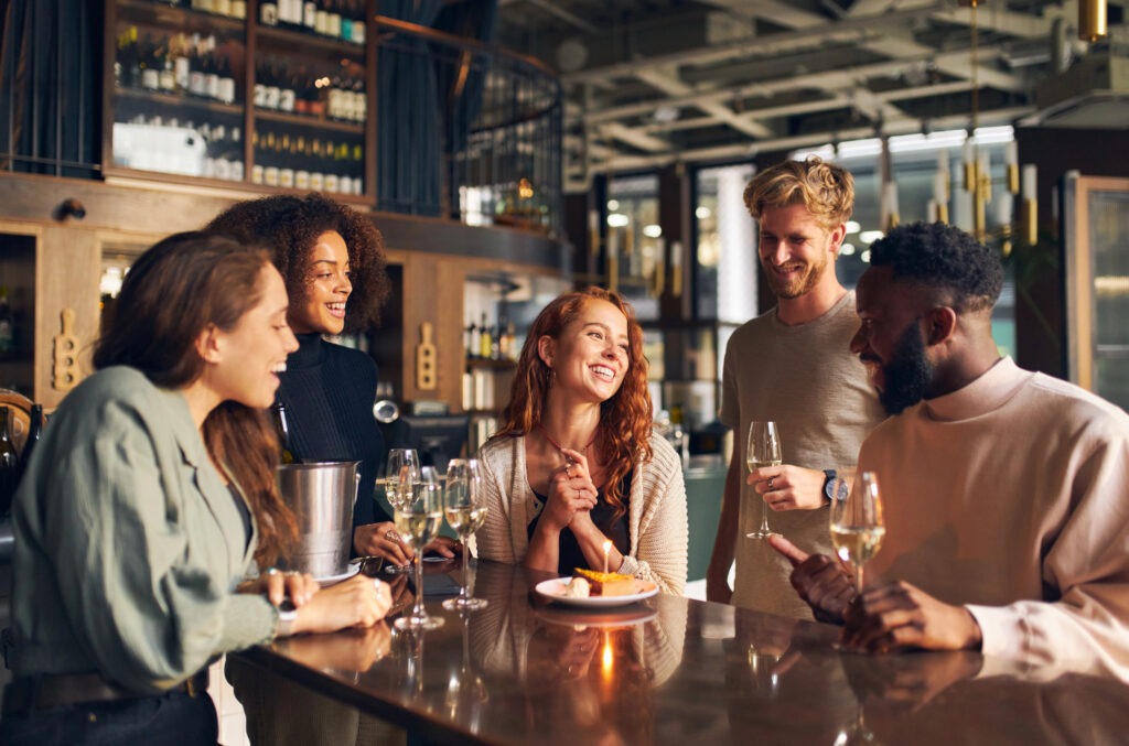 Friends laughing and enjoying glasses of wine at a bar