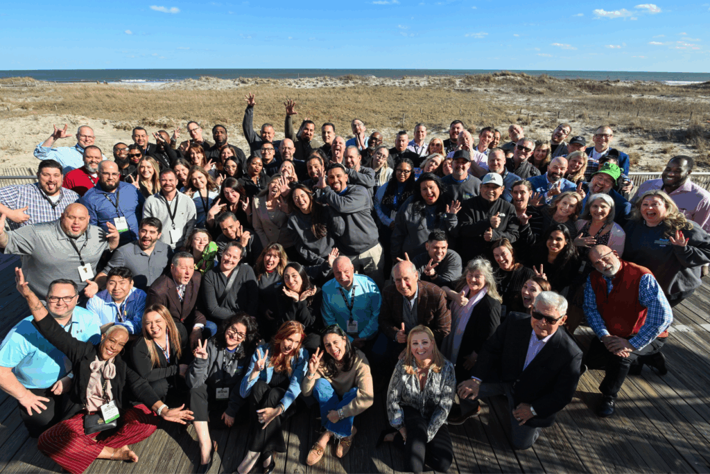 Group shot of Scully Company employees smiling at the camera on a beach boardwalk