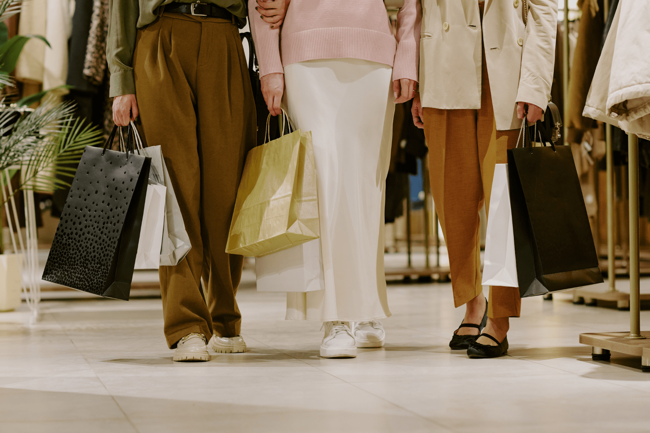 People walking through a shopping mall holding paper bags 