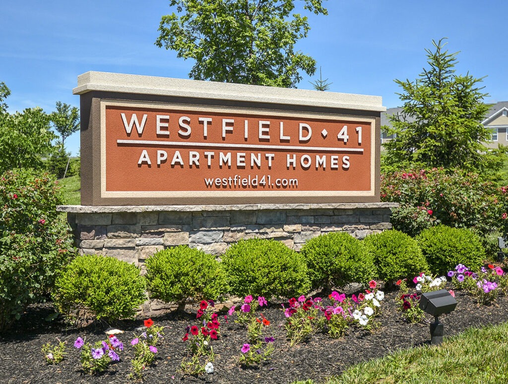 Orange sign at Westfield 41 Apartments surrounded by flowers and shrubs