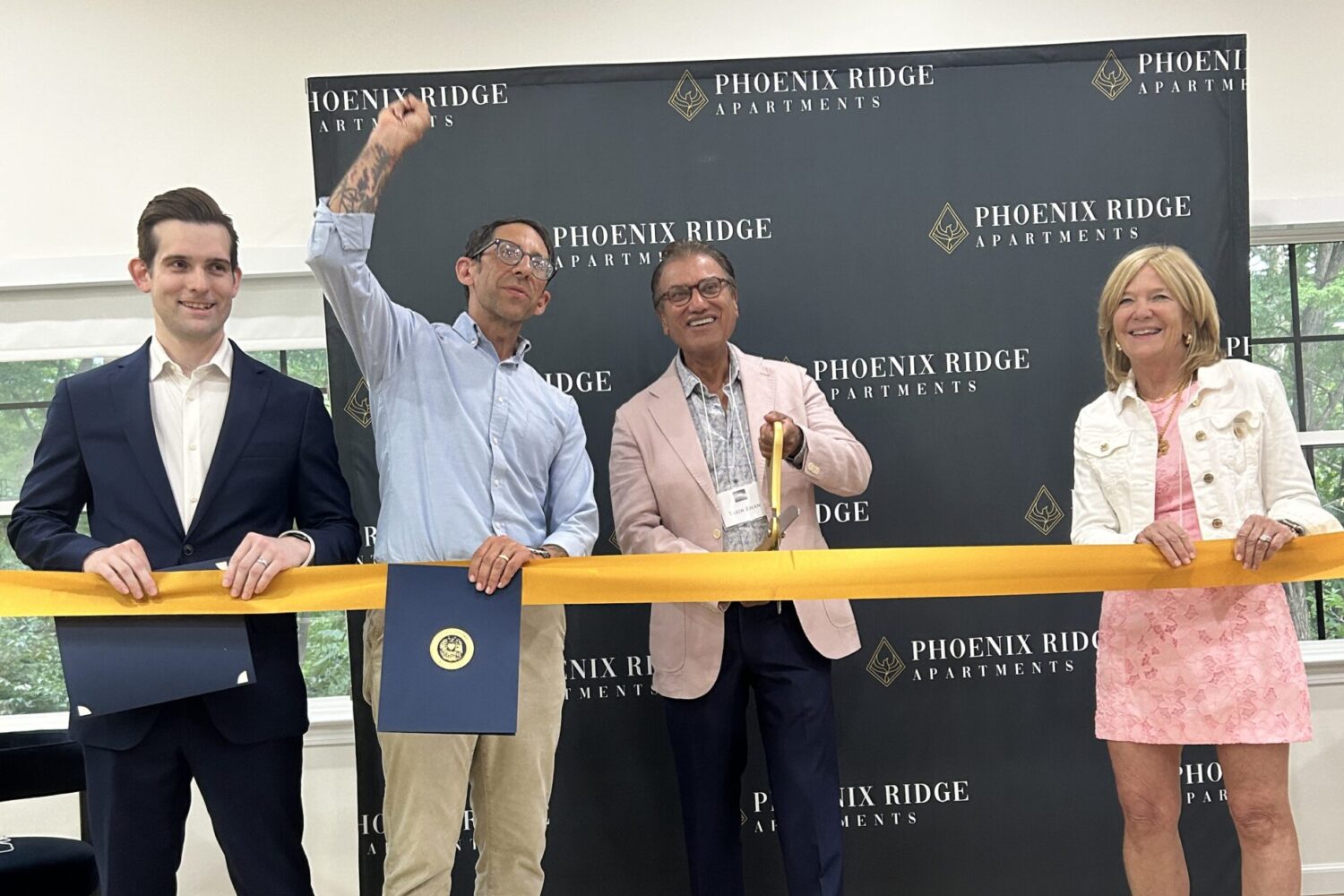 Four people with a gold ribbon doing a ribbon cutting ceremony