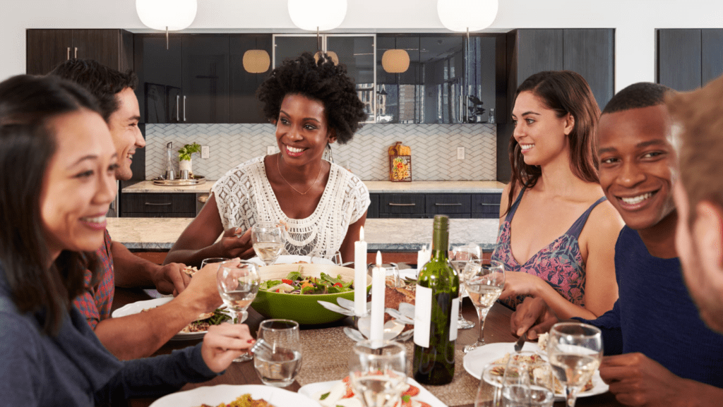 Friends sitting at a dining table eating and smiling